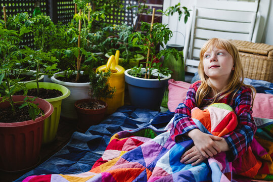 Thoughtful girl wrapped in blanket sitting in balcony