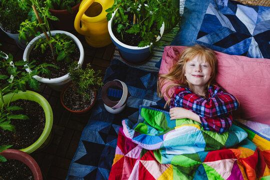 Smiling girl resting near plants in balcony