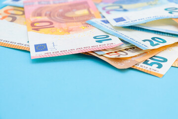10, 20 and 50 euro bills on a blue background with copy space