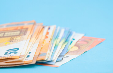 10, 20 and 50 euro bills on a blue background with copy space