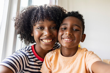 Smiling mother with son taking selfie at home