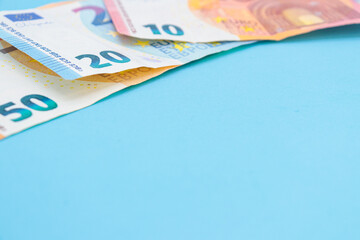 10, 20 and 50 euro bills on a blue background with copy space