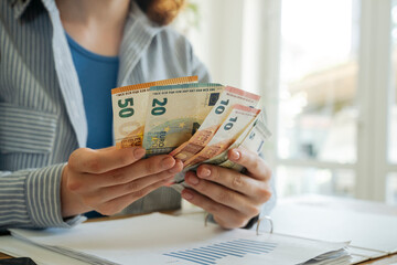 Young woman counting currency at home
