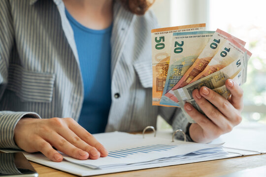 Young woman sitting with financial documents and currency at home