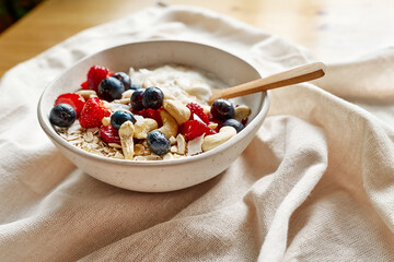 Coconut yogurt granola with strawberry, blueberry and cashew in white bowl. Concept of healthy breakfast, vegetarian meal, dieting, weight loss, healthy eating.