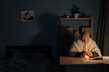 Elderly 70s man without electricity at home with candle. Shutdown of heating and electricity, power...