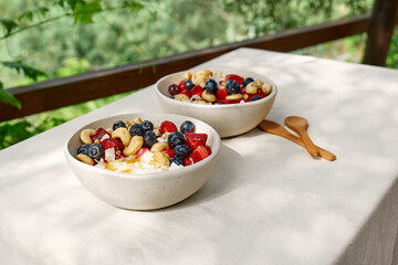 Coconut yogurt granola with strawberry, blueberry and cashew in white bowl. Concept of healthy breakfast, vegetarian meal, dieting, weight loss, healthy eating.