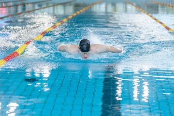 Front view of a female swimmer swimming butterfly style, a stroke performing in a competitive...
