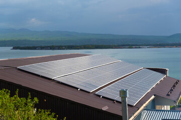 Close-up of solar panels on the roof of a house on the background of a lake, mountains