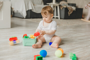 baby 6-9 months old playing with a colorful rainbow toy pyramid sitting in a white sunny bedroom. Toys for small children. Children's interior. A child with an educational toy.