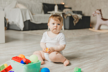 baby 6-9 months old playing with a colorful rainbow toy pyramid sitting in a white sunny bedroom. Toys for small children. Children's interior. A child with an educational toy.