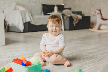baby 6-9 months old playing with a colorful rainbow toy pyramid sitting in a white sunny bedroom. Toys for small children. Children's interior. A child with an educational toy.