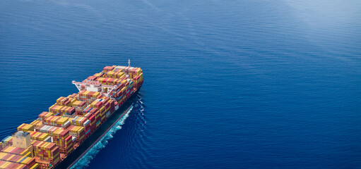 Aerial view of a large, industrial container cargo ship sailing over the ocean with copy space