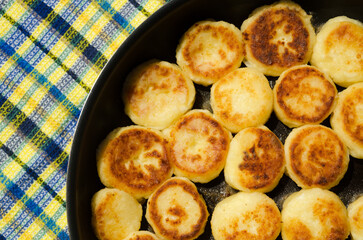 Homemade cheesecakes are fried in a pan.