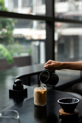 Iced coffee in glass on table in coffee shop blur background.