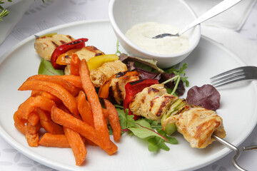 Greek souvlaki, sweet potatoe and tzatziki yogurt dip served on the plate in the restaurant