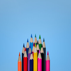Top view of lots of multicolored pencils. Empty place for text or drawing on the blue background.