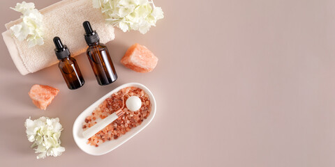 A bottle of cosmetic product on the roller of the towel , white stone massager in an oval bowl with bath salts. Top view . A copy space. banner.