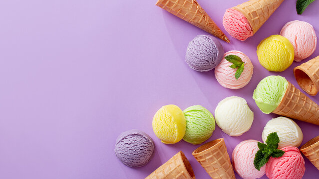 Pastel colored ice cream scoops and cones border on pastel violet background