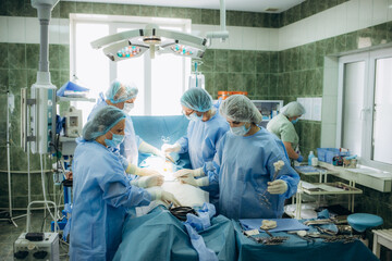 The medical team performing cesarean sections. The doctor hold the baby giving birth to his mother...