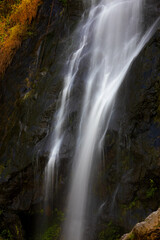 Fototapeta na wymiar Close focus on smooth flowing water from high rock waterfall.