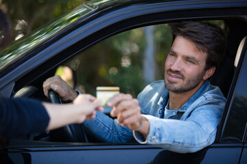happy smiling man sitting in his car showing credit card