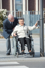 Fototapeta na wymiar old couple in wheelchair on the pedestrian crossing