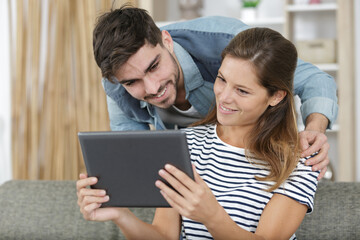 couple lying down watches video on digital tablet