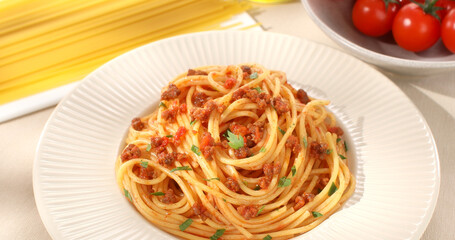 spaghetti bolognese on plate. italian pasta with meat sauce on a light background with tomato, raw spaghetti and olive oil. dish of mediterranean cuisine. food on the table on a sunny day.