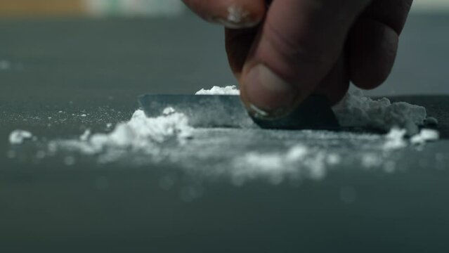 Drug addict preparing lines of heroin for injection