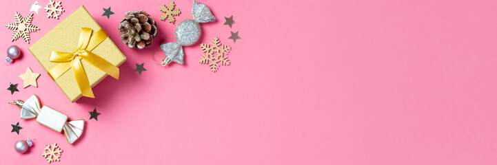 Christmas web banner with golden gift box with mini Christmas trees and shiny baubles on pastel pink background, Christmas border, copy space. Christmas gift idea, holiday presents concept