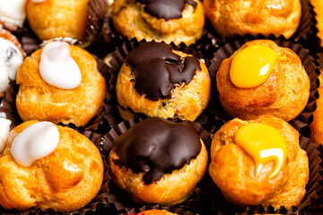 Closeup of variety of best Italian and French Pastries, dessert. Choux pastry beignets with...