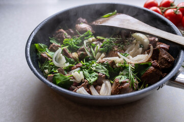 Hot frying pan with meat, herbs, onion and garlic 