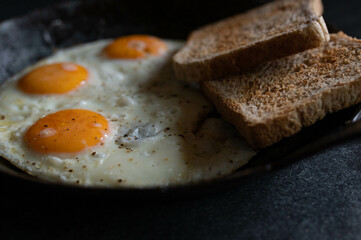 Fried eggs with toast in a cast iron pan
