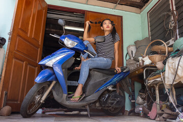 Plakat A young woman poses on a motorcycle parked in front of a house entrance