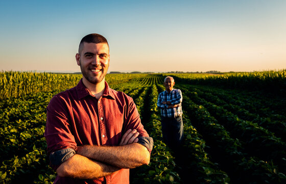 Portrait of two farmers standing in soy field at sunset.
