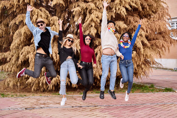 Happy and excited friends jumping while partying outdoors. Party, carnival and friendship concept.