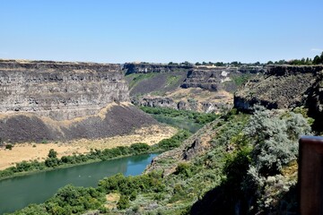 Fototapeta na wymiar Snake River cutting through a rugged gorge, framed by majestic rocky cliffs and lush green grass