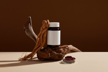 Minimalist scene for advertising and branding medicine product with herbal ingredient. Angelica sinensis roots with an empty bottle unbranded and capsules pills on brown background.