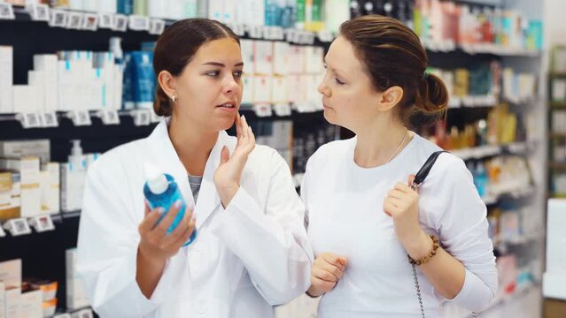 Woman pharmacist helping woman customer to choose cosmetic product