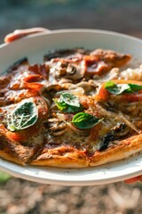 Vertical closeup of a person holding a plate with fresh pizza