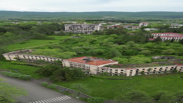 Vertical drone view of an abandoned building surrounded by green vegetation in Tskaltubo, Georgia
