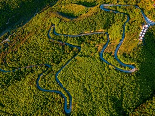 Obraz premium Aerial shot of a winding road surrounded by a lush green forest. Signagi, Georgia.