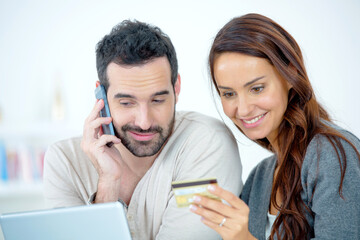 Couple with computer on telephone, holding credit card