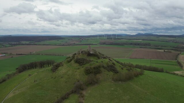 Aerial of the old Burg Desenberg castle on top of the green hill on a cloudy day