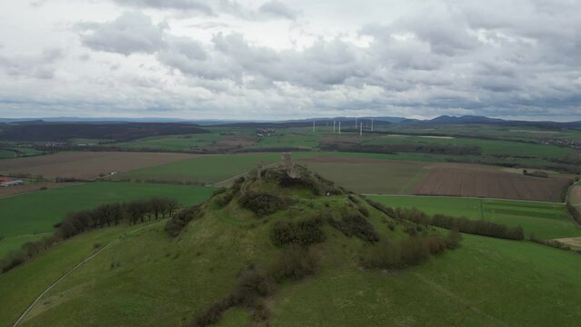 Aerial of the old Burg Desenberg castle on top of the green hill on a cloudy day