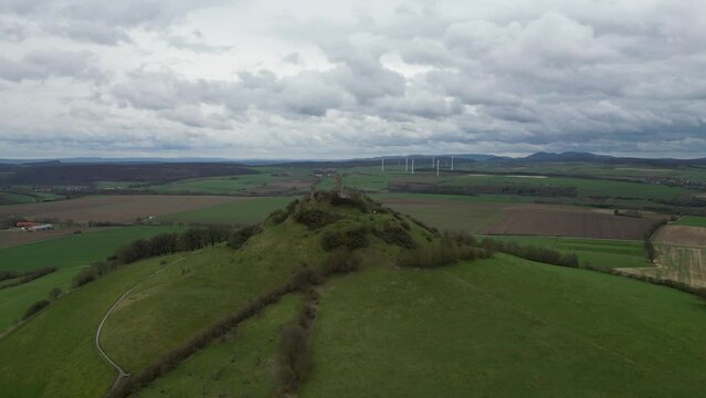 Aerial of the old Burg Desenberg castle on top of the green hill on a cloudy day