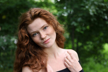 Portrait of smiling ginger girl with long red hair and freckles in summer park. Young sensual model, natural female beauty