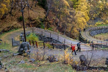 Naklejka premium Aerial view of people walking down a curvy path in a forest in autumn