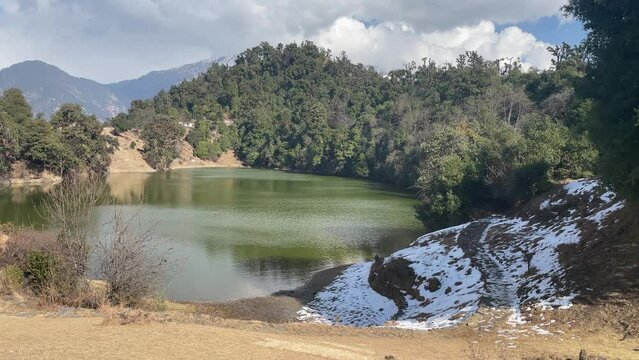 Sunny footage of Deoria Taal lake between green lush forest with cloudy sky